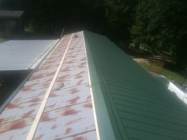 Old rusted panels beside newly installed green metal roofing — Wind Damage Roof Repair by Roofing Brothers in Summitville